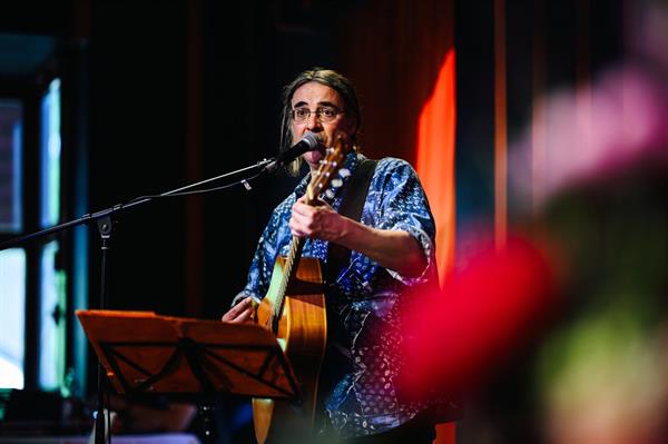 Foto von Peter auf der Bühne, mit Gitarre und Gesangsmikrofon